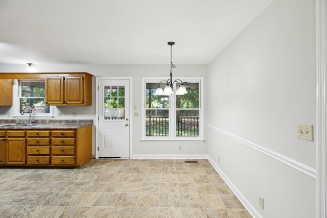 3031 Hartford Dr, Murfreesboro, TN 37129 - kitchen featuring a sink, brown cabinets, a chandelier, decorative light fixtures, and baseboards