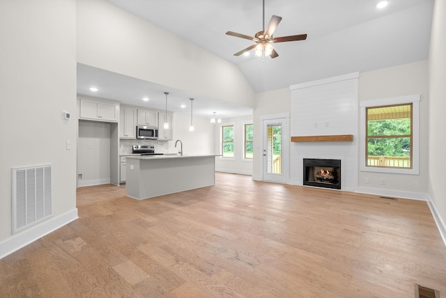 1928 Flats Rd, Cunningham, TN 37052 - unfurnished living room with a sink, light wood finished floors, a ceiling fan, a fireplace, and baseboards
