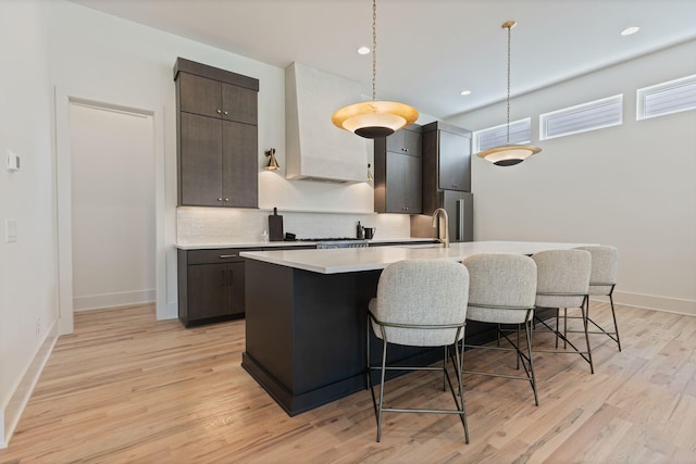 2801B W Kirkwood Ave, Nashville, TN 37204 - kitchen with a kitchen bar, light countertops, a kitchen island with sink, backsplash, and light wood-style floors