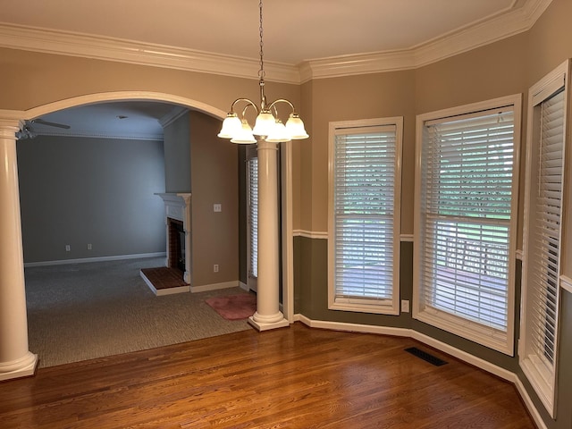 95 Dundee Cir, Mcminnville, TN 37110 - unfurnished dining area featuring crown molding, arched walkways, a chandelier, decorative columns, and wood finished floors