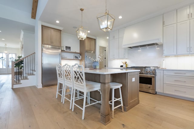 4761 Woodrow Pl, Arrington, TN 37014 - kitchen with premium appliances, a kitchen island with sink, decorative backsplash, light wood finished floors, and a kitchen breakfast bar