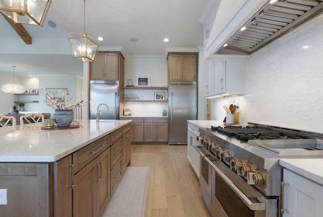4761 Woodrow Pl, Arrington, TN 37014 - kitchen featuring high end appliances, wall chimney exhaust hood, a chandelier, light wood-type flooring, and open shelves