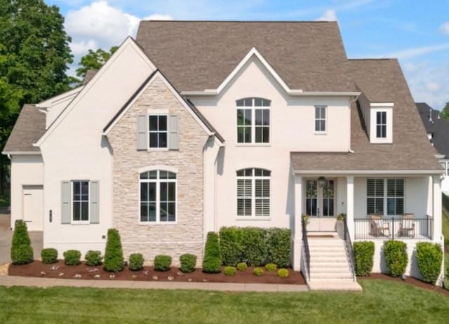 4761 Woodrow Pl, Arrington, TN 37014 - view of front of property with stone siding, a front lawn, a shingled roof, french doors, and covered porch