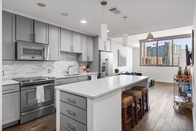 1212 Laurel St Unit 206, Nashville, TN 37203 - kitchen featuring appliances with stainless steel finishes, gray cabinets, a sink, a center island, and backsplash