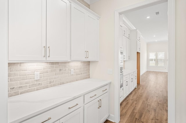 7503 Old Nashville Rd, Fairview, TN 37062 - kitchen featuring white cabinetry, backsplash, light stone counters, light wood finished floors, and stainless steel oven