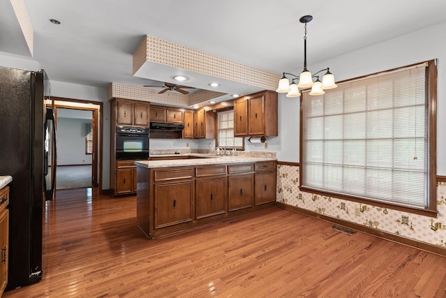 7125 Bidwell Rd, Joelton, TN 37080 - kitchen with black appliances, baseboards, wallpapered walls, wood finished floors, and a peninsula
