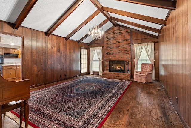 7125 Bidwell Rd, Joelton, TN 37080 - unfurnished living room featuring dark wood-style floors, a chandelier, wood walls, and a brick fireplace