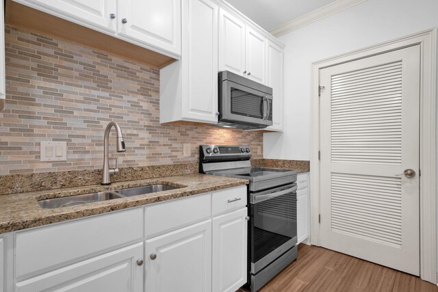 1010 16th Ave S Unit 301, Nashville, TN 37212 - kitchen with appliances with stainless steel finishes, a sink, ornamental molding, decorative backsplash, and white cabinetry