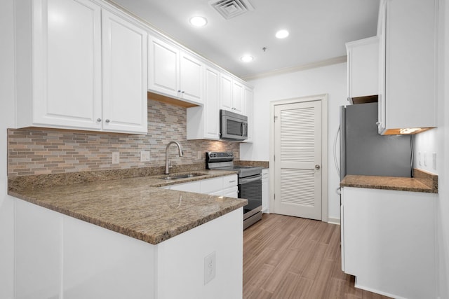 1010 16th Ave S Unit 301, Nashville, TN 37212 - kitchen featuring a sink, stainless steel appliances, white cabinetry, backsplash, and a peninsula