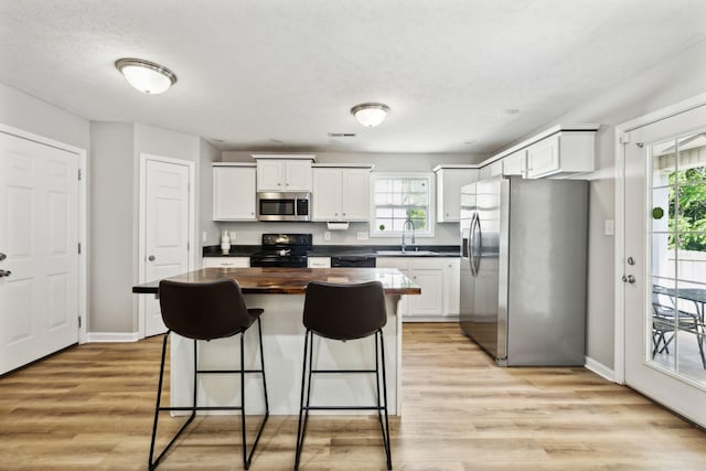 215 Azalea Dr, Oak Grove, KY 42262 - kitchen with appliances with stainless steel finishes, a kitchen bar, white cabinetry, wooden counters, and light wood-type flooring