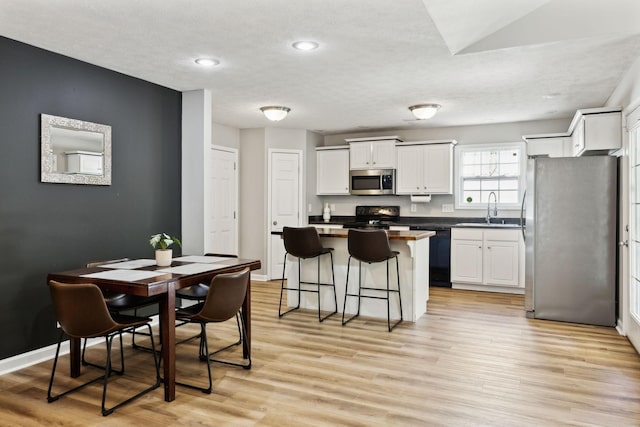 215 Azalea Dr, Oak Grove, KY 42262 - kitchen with black appliances, a kitchen island, a sink, a breakfast bar area, and white cabinetry