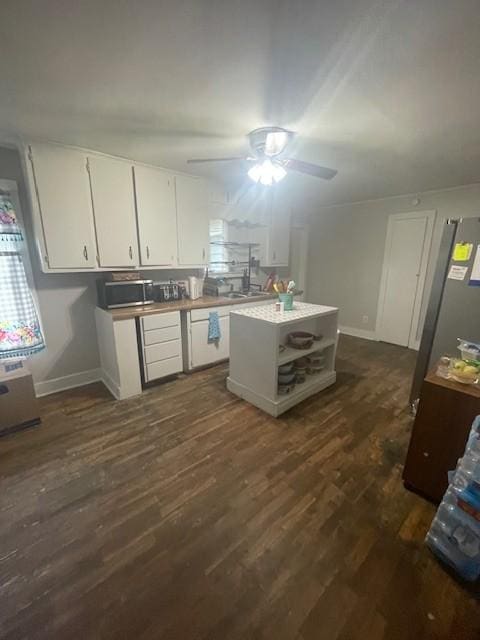 103 E High St, Ethridge, TN 38456 - kitchen with white cabinets, a ceiling fan, dark wood-style flooring, stainless steel microwave, and a center island