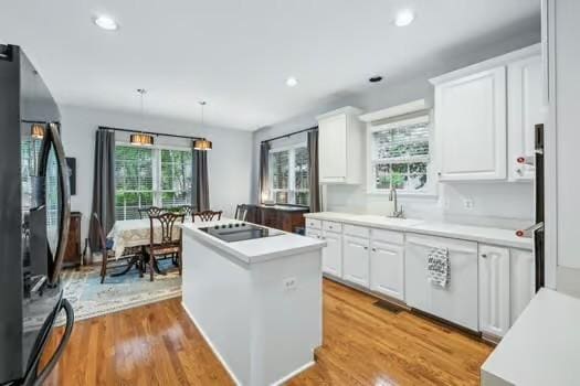 200 Heathstone Cir, Franklin, TN 37069 - kitchen featuring a center island, white cabinets, black appliances, light countertops, and light wood finished floors