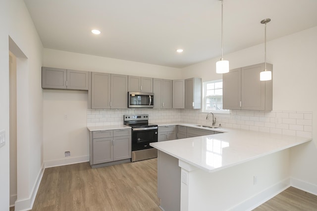 324 Fieldstone Ln, Springfield, TN 37172 - kitchen featuring appliances with stainless steel finishes, gray cabinetry, a sink, a peninsula, and light wood-style flooring