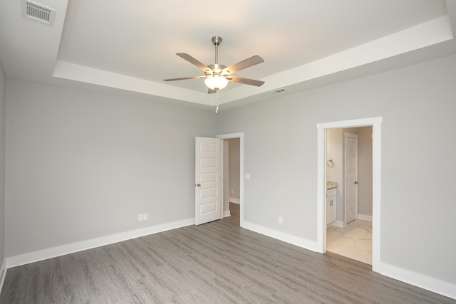 302 Fieldstone Ln, Springfield, TN 37172 - unfurnished bedroom featuring a tray ceiling, light wood-style flooring, baseboards, ensuite bathroom, and a ceiling fan