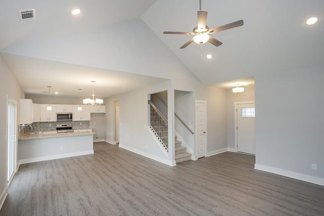 302 Fieldstone Ln, Springfield, TN 37172 - unfurnished living room with high vaulted ceiling, a sink, stairway, wood finished floors, and a chandelier