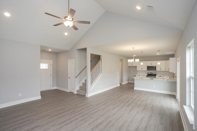 340 Fieldstone Ln, Springfield, TN 37172 - unfurnished living room featuring high vaulted ceiling, stairway, ceiling fan, wood finished floors, and recessed lighting