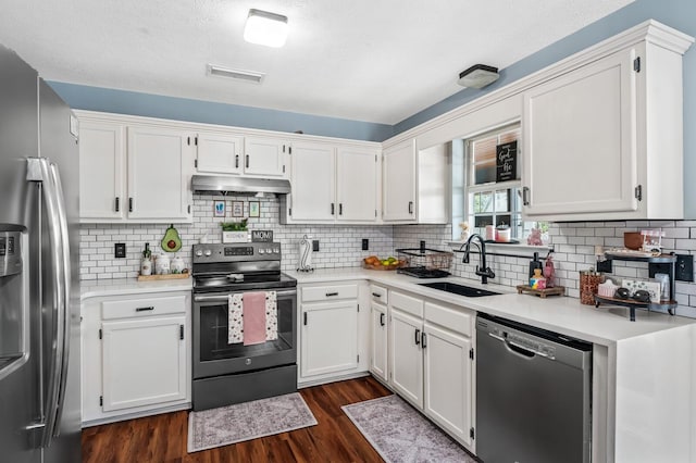 304 Hank Aaron Cv, La Vergne, TN 37086 - kitchen with appliances with stainless steel finishes, a sink, under cabinet range hood, dark wood finished floors, and white cabinets