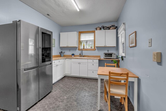 1049 E Trinity Ln, Nashville, TN 37216 - kitchen with smart refrigerator, butcher block countertops, a sink, white cabinetry, and a textured ceiling