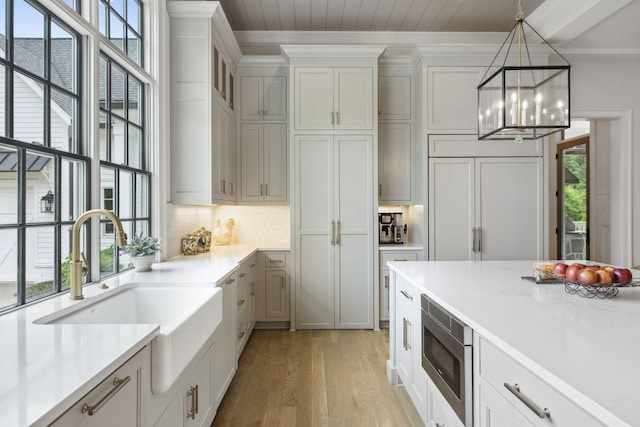 8118 Heirloom Blvd, College Grove, TN 37046 - kitchen with stainless steel microwave, a sink, a chandelier, light wood-type flooring, and light countertops