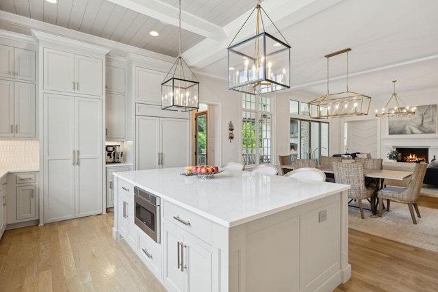 8118 Heirloom Blvd, College Grove, TN 37046 - kitchen with light wood-style flooring, stainless steel microwave, a chandelier, decorative light fixtures, and beamed ceiling