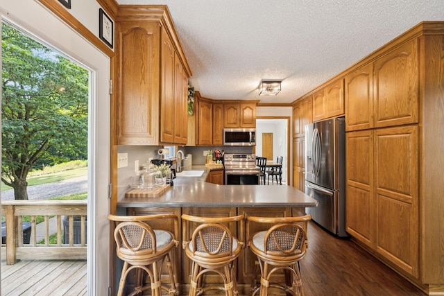 345 Big Spring Hollow Rd, Pulaski, TN 38478 - kitchen featuring stainless steel appliances, dark wood-type flooring, a peninsula, a textured ceiling, and brown cabinets