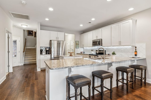 2037 Flowing Creek Dr, Franklin, TN 37064 - kitchen with stainless steel appliances, a sink, a peninsula, decorative backsplash, and light stone countertops