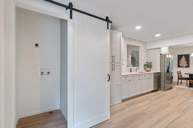 4900 Chesterfield Dr, Murfreesboro, TN 37127 - kitchen featuring appliances with stainless steel finishes, a barn door, a sink, light countertops, and light wood-style floors