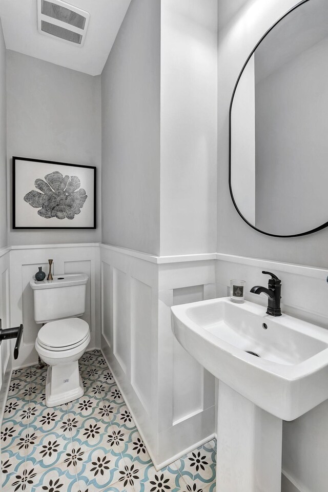 2670 Morgan Rd, Joelton, TN 37080 - half bath featuring toilet, a sink, wainscoting, a decorative wall, and tile patterned flooring