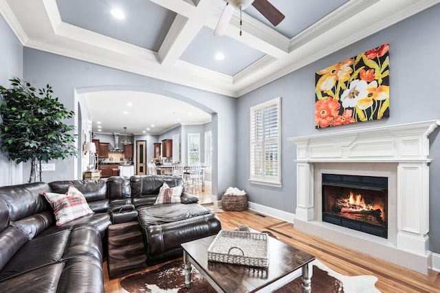 3009 Burnley Ct, Spring Hill, TN 37174 - living room with arched walkways, ceiling fan, light wood-type flooring, a warm lit fireplace, and ornamental molding