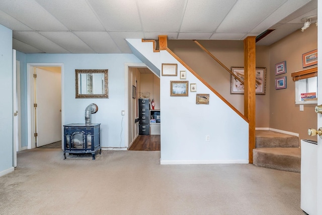 192 Askin Ln, Baxter, TN 38544 - unfurnished living room featuring a wood stove, carpet flooring, stairs, a paneled ceiling, and baseboards