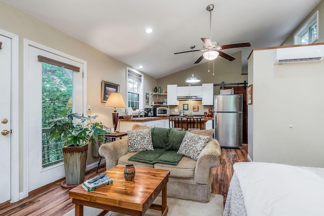 192 Askin Ln, Baxter, TN 38544 - living area with a wall unit AC, a barn door, wood finished floors, a ceiling fan, and vaulted ceiling