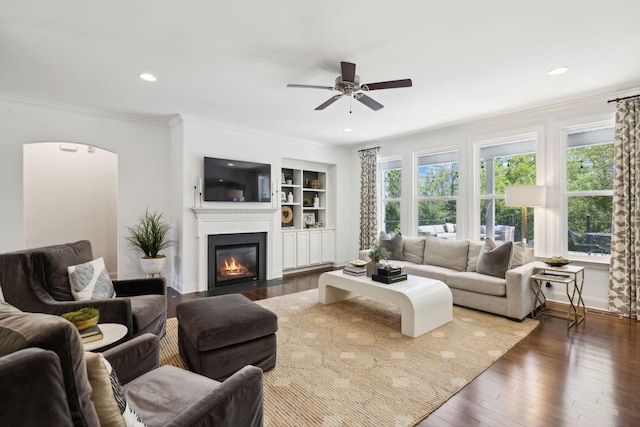 410 Dabney Dr, Franklin, TN 37064 - living room featuring a ceiling fan, a fireplace with flush hearth, dark wood finished floors, arched walkways, and ornamental molding