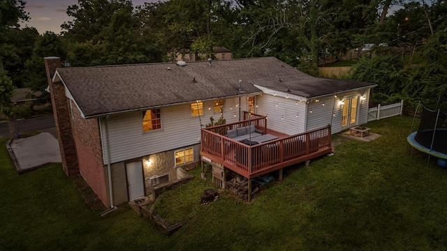 1310 Tabitha Dr, Hixson, TN 37343 - back of house at dusk with a trampoline, a chimney, a wooden deck, and a shingled roof