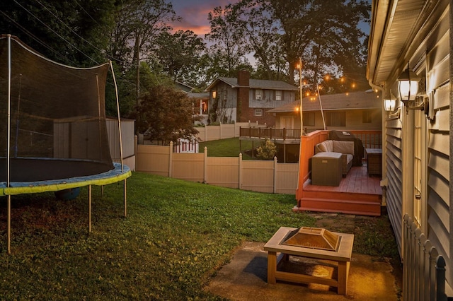 1310 Tabitha Dr, Hixson, TN 37343 - yard at dusk with a trampoline, a deck, and an outdoor fire pit