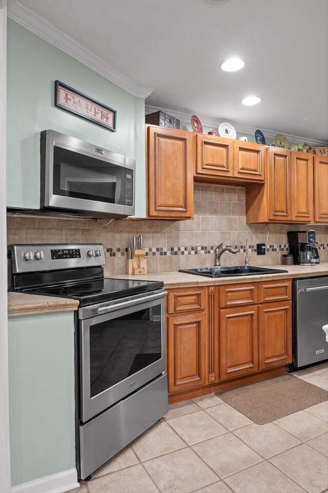 1310 Tabitha Dr, Hixson, TN 37343 - kitchen featuring appliances with stainless steel finishes, ornamental molding, a sink, light countertops, and decorative backsplash