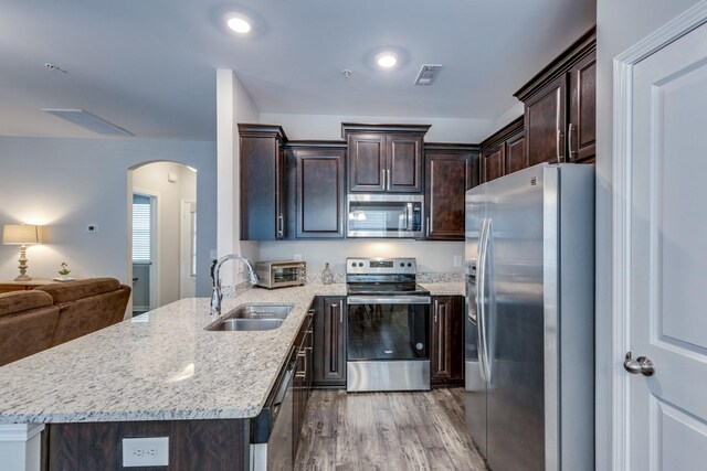 221 Kinsale Dr, Spring Hill, TN 37174 - kitchen with stainless steel appliances, a sink, arched walkways, dark brown cabinets, and a peninsula