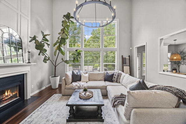 5517 Nevil Pt, Brentwood, TN 37027 - living room with a towering ceiling, wood finished floors, a warm lit fireplace, baseboards, and a chandelier