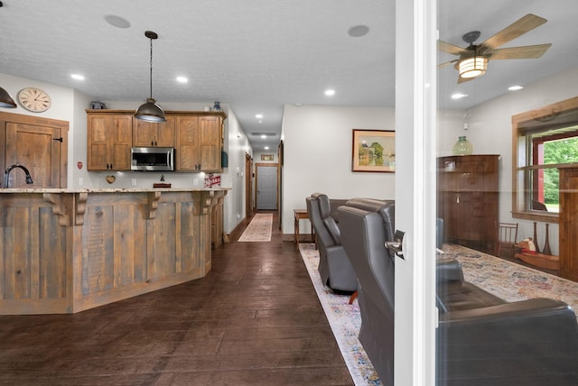4499 Benson Rd, Springfield, TN 37172 - kitchen with stainless steel microwave, a kitchen breakfast bar, brown cabinetry, ceiling fan, and light stone countertops
