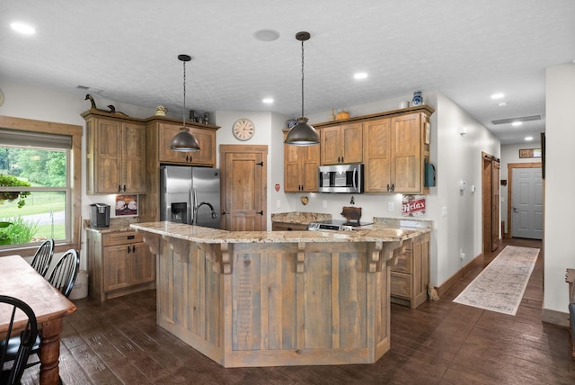 4499 Benson Rd, Springfield, TN 37172 - kitchen with appliances with stainless steel finishes, a center island with sink, dark wood-style flooring, light stone counters, and brown cabinetry