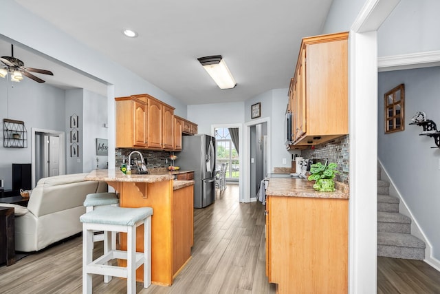 116 Macy Ct, Christiana, TN 37037 - kitchen featuring appliances with stainless steel finishes, a breakfast bar area, a ceiling fan, a peninsula, and decorative backsplash