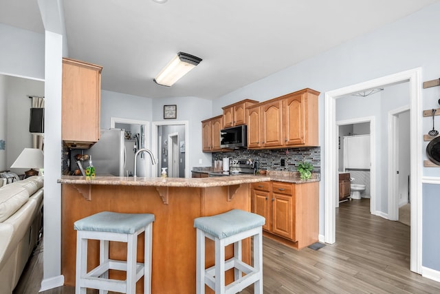 116 Macy Ct, Christiana, TN 37037 - kitchen featuring appliances with stainless steel finishes, a kitchen breakfast bar, backsplash, and light wood-style flooring