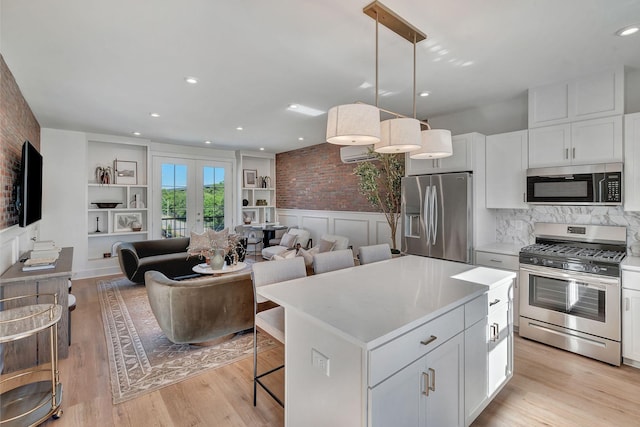 603 51st Ave, Nashville, TN 37209 - kitchen with stainless steel appliances, white cabinets, light countertops, a kitchen island, and a wainscoted wall