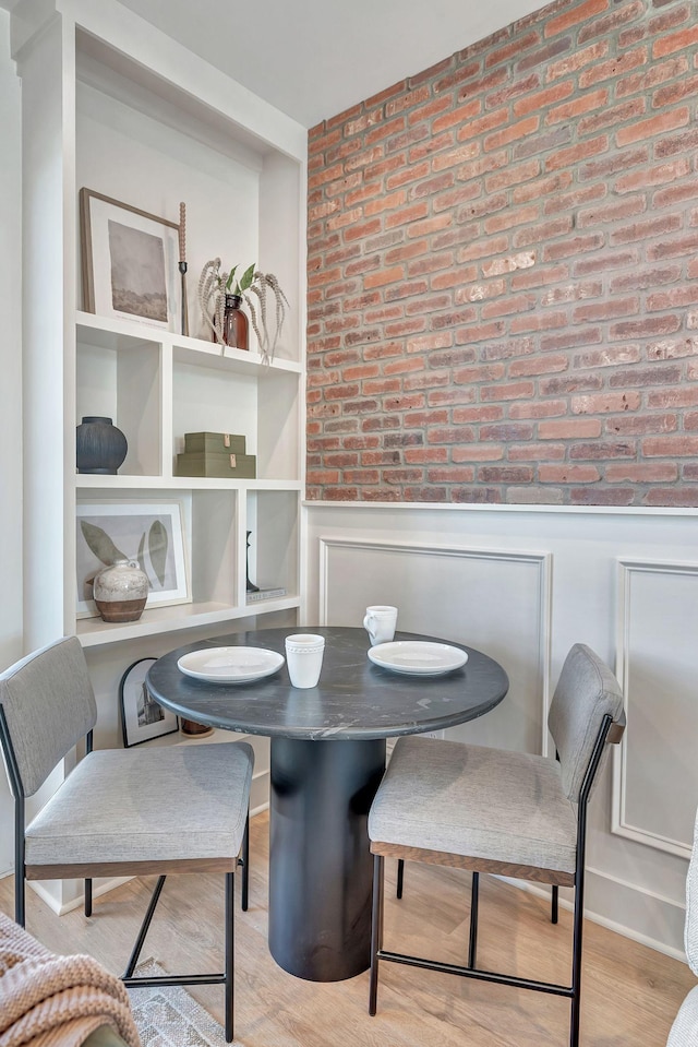 603 51st Ave, Nashville, TN 37209 - dining room featuring a wainscoted wall, brick wall, wood finished floors, and a decorative wall