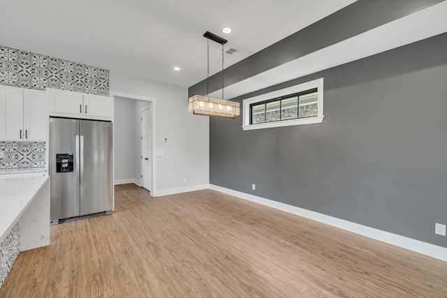 415 S University St, Murfreesboro, TN 37130 - kitchen with stainless steel fridge with ice dispenser, white cabinets, light wood-type flooring, hanging light fixtures, and decorative backsplash