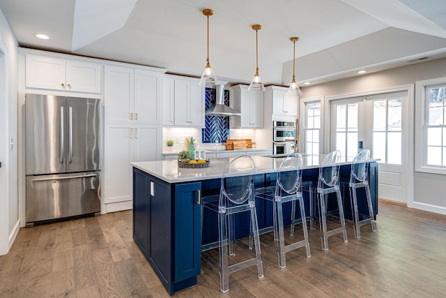 4626 Cato Rd, Nashville, TN 37218 - kitchen featuring stainless steel appliances, wall chimney range hood, white cabinetry, a spacious island, and wood finished floors