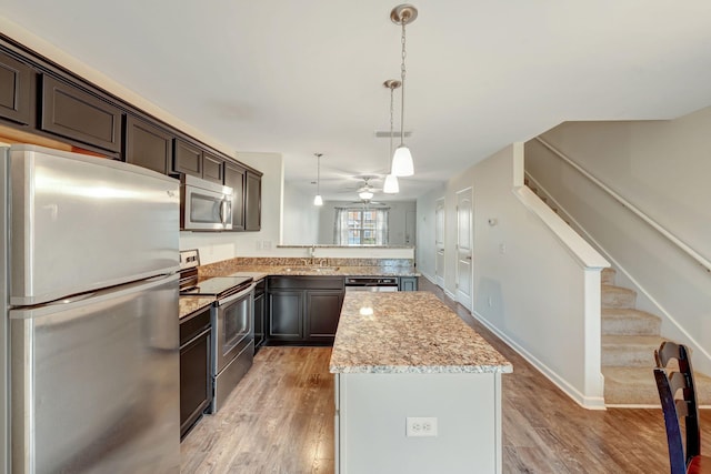 133 Cobblestone Place Dr, Goodlettsville, TN 37072 - kitchen with stainless steel appliances, a sink, a center island, dark brown cabinetry, and light wood-style floors