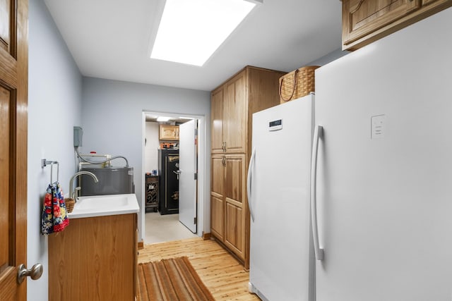 29 Roger Monk Rd, Petersburg, TN 37144 - kitchen featuring light wood-style flooring, freestanding refrigerator, brown cabinetry, a sink, and light countertops