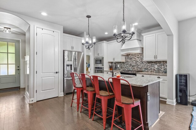 705 Rain Meadow Ct, Spring Hill, TN 37174 - kitchen featuring stainless steel appliances, a kitchen island with sink, a kitchen bar, tasteful backsplash, and white cabinets