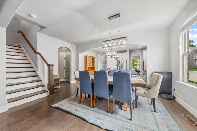 705 Rain Meadow Ct, Spring Hill, TN 37174 - dining area featuring arched walkways, stairway, dark wood finished floors, a chandelier, and healthy amount of natural light